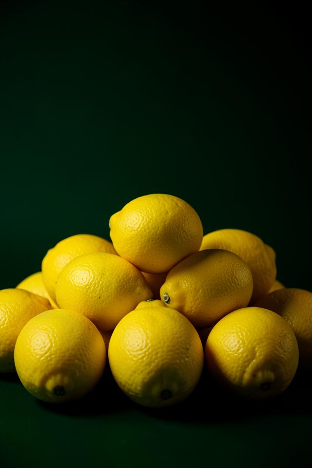 Fresh yellow lemons with green leaves on a light surface